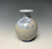 Load image into Gallery viewer, a small porcelain bud vase with a zinc crystalline glaze that has a light lavender colored crystals on a grey gradient background