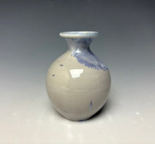 Load image into Gallery viewer, a small porcelain bud vase with a zinc crystalline glaze that has a light lavender colored crystals on a grey gradient background