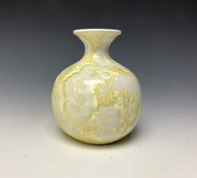 Load image into Gallery viewer, a small porcelain bud vase with a zinc crystalline glaze that has a ivory and cream colored crystals on a grey gradient background