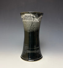 Load image into Gallery viewer, a black vase with light white, foamy looking, area along the top 1/3 of the vase. The vase is pictured on a grey gradient background.