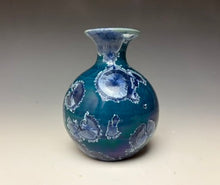 Load image into Gallery viewer, a small porcelain bud vase with a zinc crystalline glaze that has a deep blue colored crystals on a grey gradient background