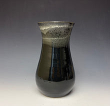 Load image into Gallery viewer, a black vase with light white, foamy looking, area along the top 1/3 of the vase. The vase is pictured on a grey gradient background.
