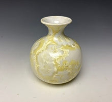 Load image into Gallery viewer, a small porcelain bud vase with a zinc crystalline glaze that has a ivory and cream colored crystals on a grey gradient background
