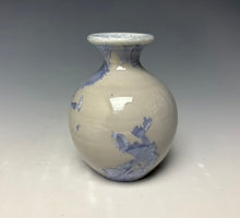Load image into Gallery viewer, a small porcelain bud vase with a zinc crystalline glaze that has a light lavender colored crystals on a grey gradient background
