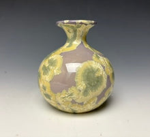Load image into Gallery viewer, a small porcelain bud vase with a zinc crystalline glaze that has a light lavender base with cream/grey colored crystals on a grey gradient background
