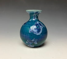 Load image into Gallery viewer, a small porcelain bud vase with a zinc crystalline glaze that has a deep blue colored crystals on a grey gradient background
