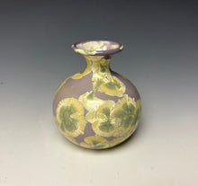 Load image into Gallery viewer, a small porcelain bud vase with a zinc crystalline glaze that has a light lavender base with cream/grey colored crystals on a grey gradient background
