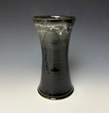 Load image into Gallery viewer, a black vase with light white, foamy looking, area along the top 1/3 of the vase. The vase is pictured on a grey gradient background.
