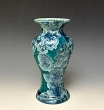 Load image into Gallery viewer, A ceramic vase with a flared rim and bulbous body, featuring a glossy teal and blue floral pattern with white marbled highlights, set against a dark gray gradient background.
