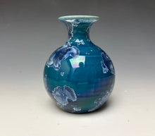 Load image into Gallery viewer, a small porcelain bud vase with a zinc crystalline glaze that has a deep blue colored crystals on a grey gradient background
