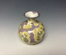 Load image into Gallery viewer, a small porcelain bud vase with a zinc crystalline glaze that has a a purple base with cream/grey colored crystals on a grey gradient background
