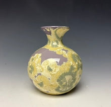 Load image into Gallery viewer, a small porcelain bud vase with a zinc crystalline glaze that has a purple base and cream and grey colored crystals on a grey gradient background
