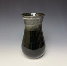 Load image into Gallery viewer, a black vase with light white, foamy looking, area along the top 1/3 of the vase. The vase is pictured on a grey gradient background.
