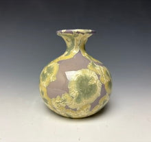Load image into Gallery viewer, a small porcelain bud vase with a zinc crystalline glaze that has a light lavender base with cream/grey colored crystals on a grey gradient background
