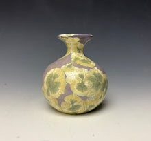 Load image into Gallery viewer, a small porcelain bud vase with a zinc crystalline glaze that has a light lavender base with cream/grey colored crystals on a grey gradient background
