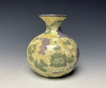 Load image into Gallery viewer, a small porcelain bud vase with a zinc crystalline glaze that has a a purple base with cream/grey colored crystals on a grey gradient background
