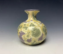 Load image into Gallery viewer, a small porcelain bud vase with a zinc crystalline glaze that has a a purple base with cream/grey colored crystals on a grey gradient background

