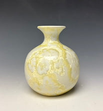 Load image into Gallery viewer, a small porcelain bud vase with a zinc crystalline glaze that has a ivory and cream colored crystals on a grey gradient background
