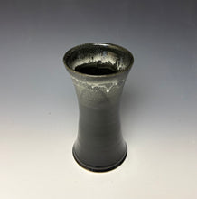 Load image into Gallery viewer, a black vase with light white, foamy looking, area along the top 1/3 of the vase. The vase is pictured on a grey gradient background.
