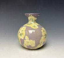 Load image into Gallery viewer, a small porcelain bud vase with a zinc crystalline glaze that has a purple base and cream and grey colored crystals on a grey gradient background
