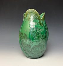 Load image into Gallery viewer, A green ceramic tulip shaped vase with a glossy finish and embossed floral patterns, photographed against a dark gray to light gray studio background.
