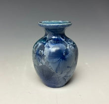 Load image into Gallery viewer, a small porcelain bud vase with a zinc crystalline glaze that has a deep teal blue base with silver/blue colored crystals on a grey gradient background
