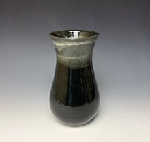 Load image into Gallery viewer, a black vase with light white, foamy looking, area along the top 1/3 of the vase. The vase is pictured on a grey gradient background.
