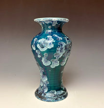 Load image into Gallery viewer, A vintage-style ceramic vase with a flared rim, featuring a glossy teal and green body decorated with raised, light blue and white zinc crystals on the surface, set against a neutral gradient background.

