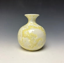 Load image into Gallery viewer, a small porcelain bud vase with a zinc crystalline glaze that has a ivory and cream colored crystals on a grey gradient background
